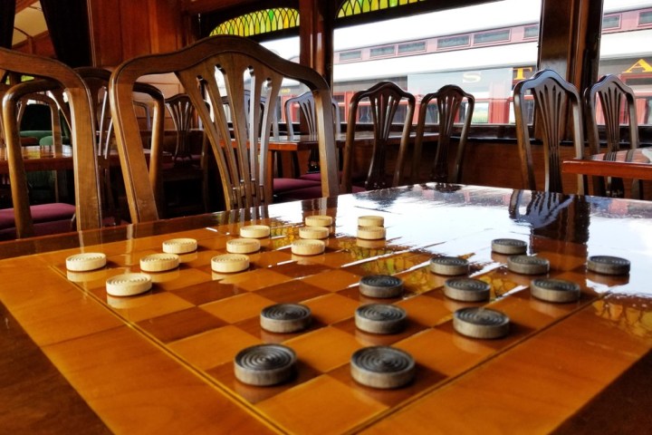 A wooden dining table with old fashioned games on top.