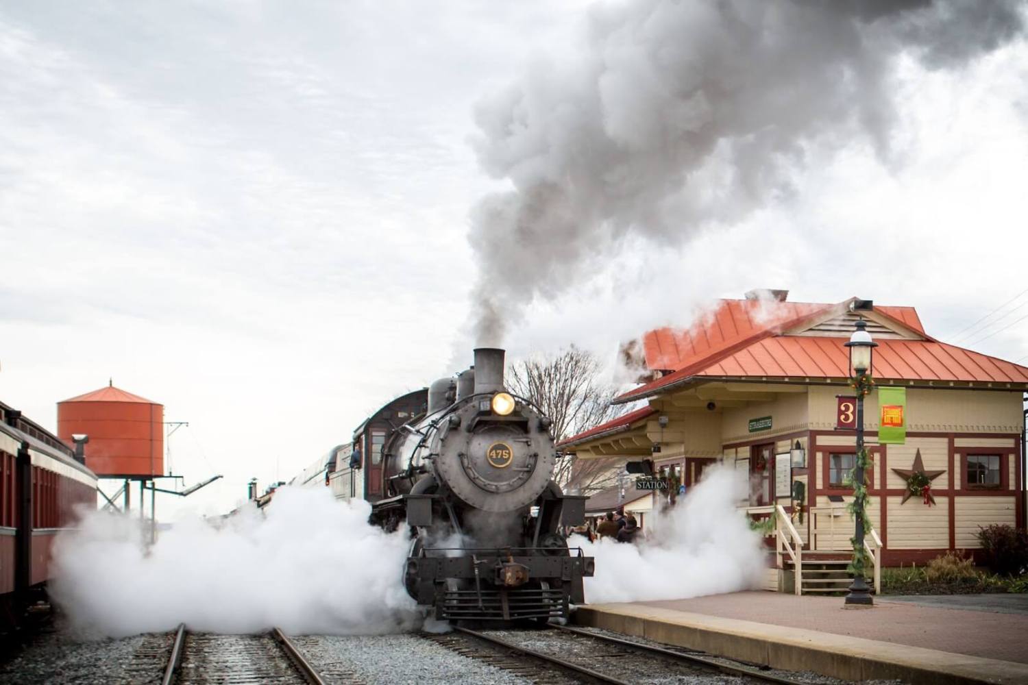 A steam engine on a train track with smoke coming out of it.