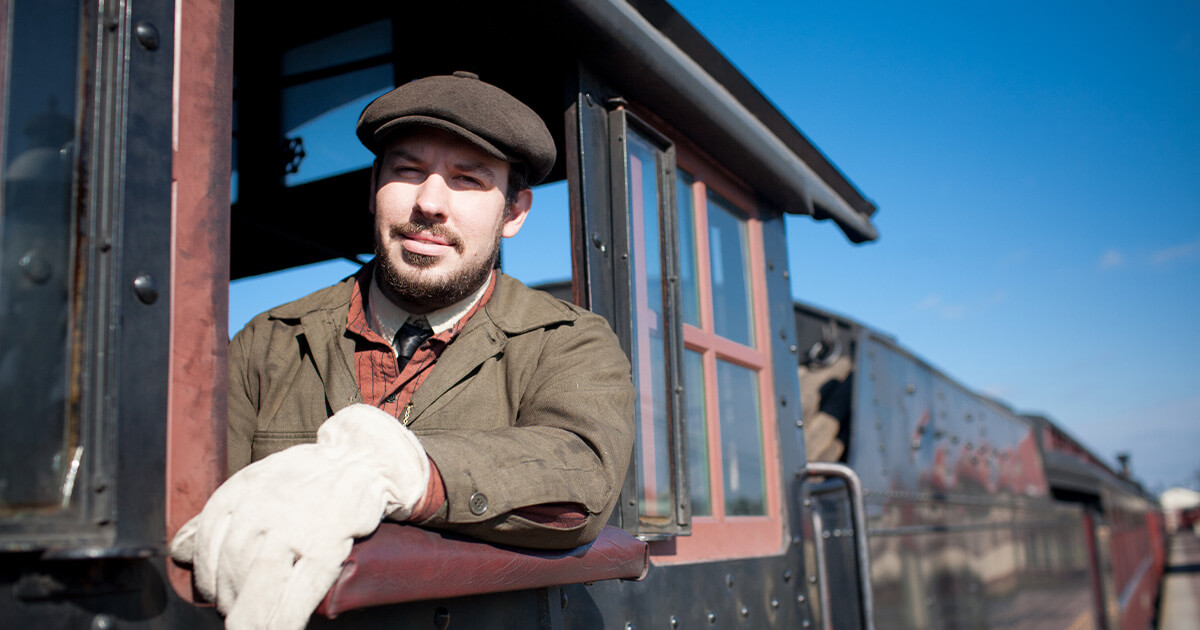 A locomotive engineer peering out the window of his seat.