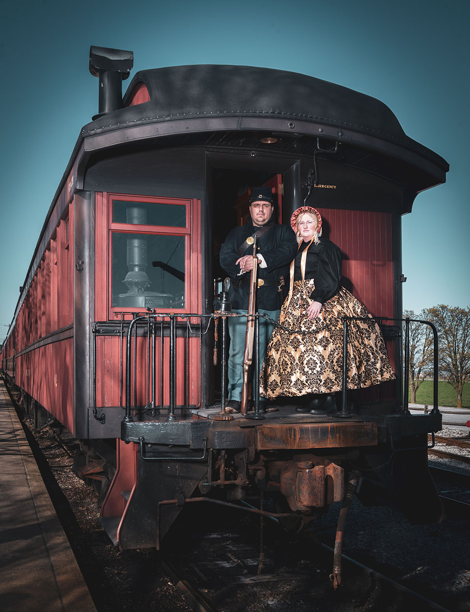 Two people in costumes standing on the balcony of a train.