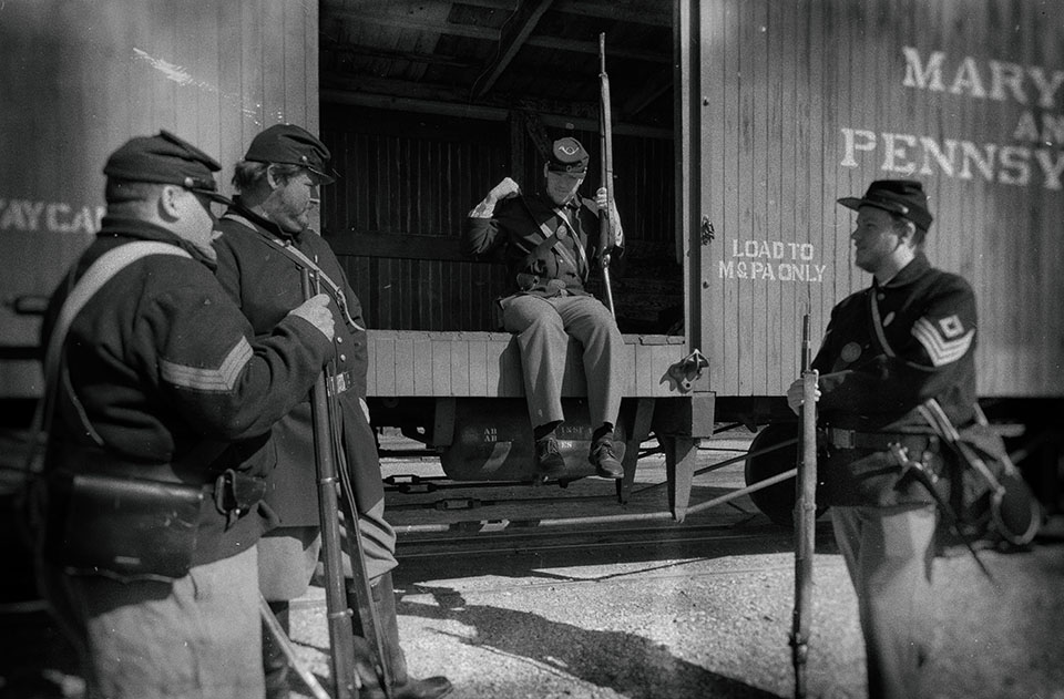 A group of people in uniform hanging out around a train car.